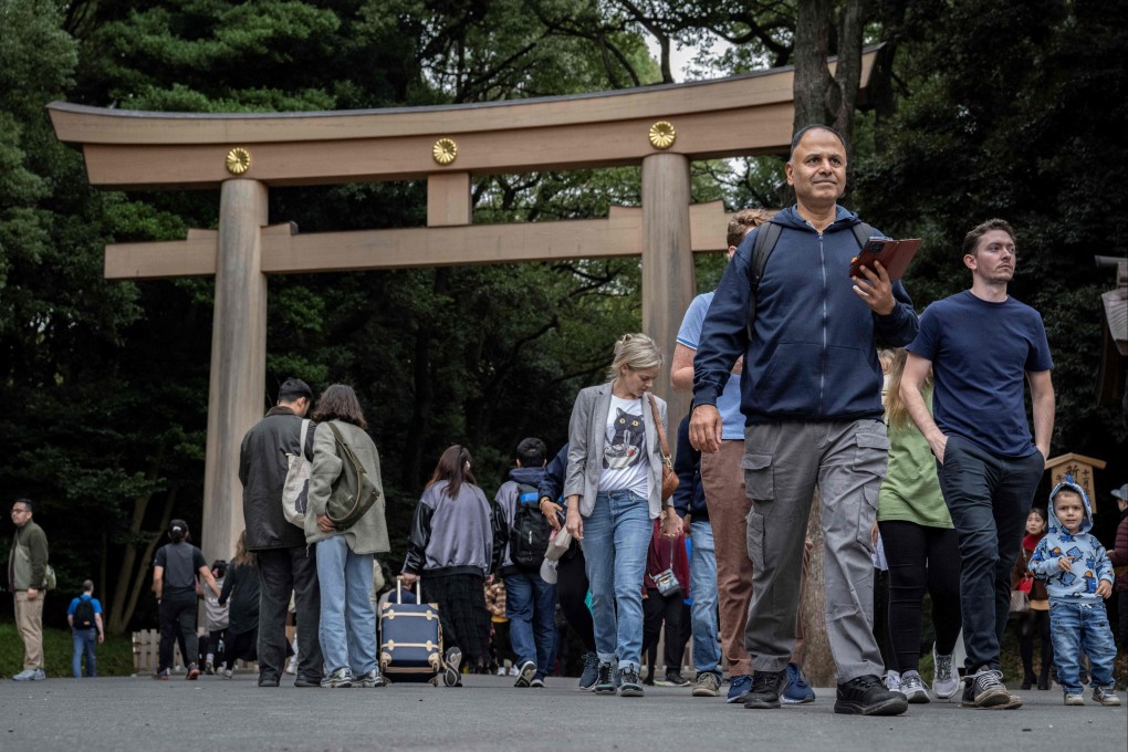 東京の明治神宮の鳥居の前を歩く人々。アメリカ人観光客が東京の神社の伝統的な木製の鳥居に文字を刻んだとして逮捕された。写真：AFP
