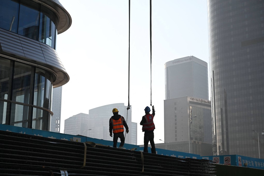 Workers prepare to attach equipment to be lifted by a crane on a construction site in the central business district in Beijing. Photo: AFP