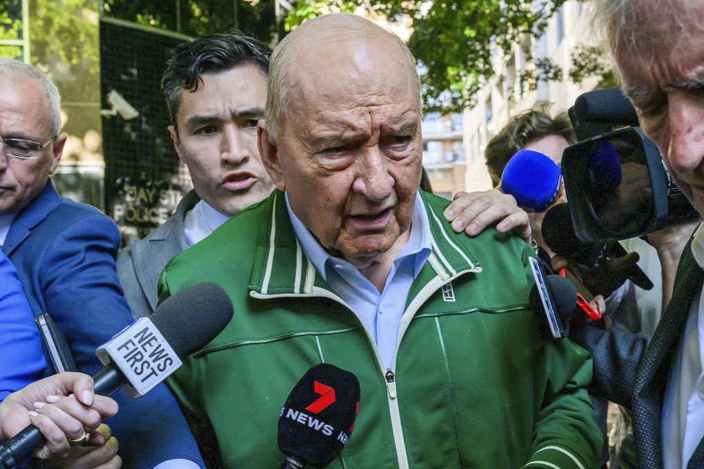 Retired broadcaster Alan Jones (centre) walks past waiting media as he leaves a police station in Sydney on Monday. Photo: AAP Image via AP