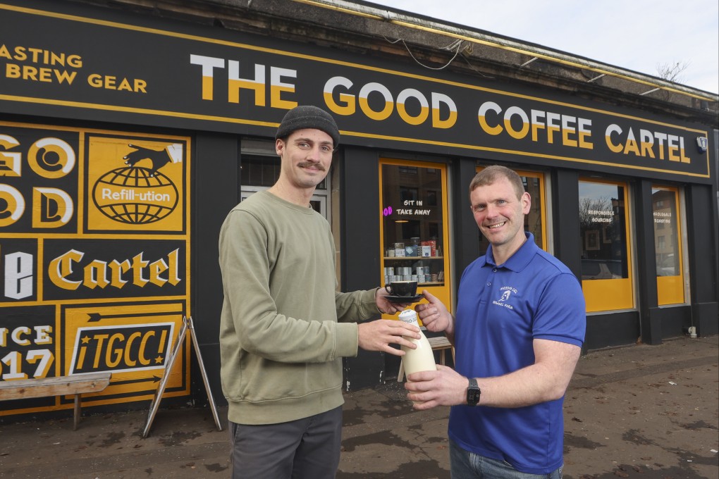 Farmer and owner of Mossgiel Organic Farm Bryce Cunningham (right) gives a bottle of milk to barista Jacob Smith, outside The Good Coffee Cartel in Glasgow. Photo: AP
