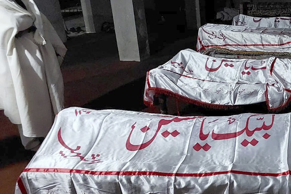 A mourner stands beside the bodies of some of the 40 people killed when gunmen opened fire on a convoy of buses in Pakistan. Photo: AP