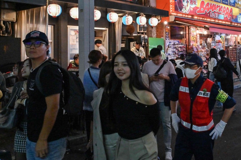 Visitors walk past restaurants in a popular tourist area next to the rail tracks in the Ueno district of central Tokyo on November 17. Photo: AFP