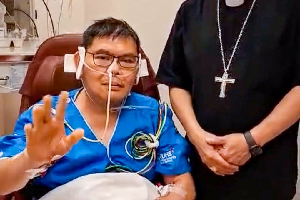 Father Christopher Lee (left) waves from his hospital room after being stabbed while he was distributing communion during the November 9 children’s evening Mass at St. Joseph’s Church in Upper Bukit Timah, Singapore. Photo: Facebook/William Cardinal Goh