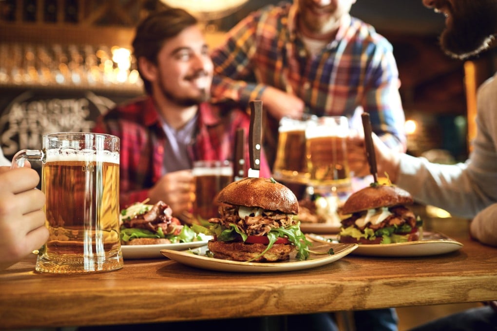 Men enjoy beers and burgers. Researchers say beer drinkers have lower-quality diets than wine drinkers, and this could in part be down to the low-fibre foods typically served at pubs. Photo: Shutterstock
