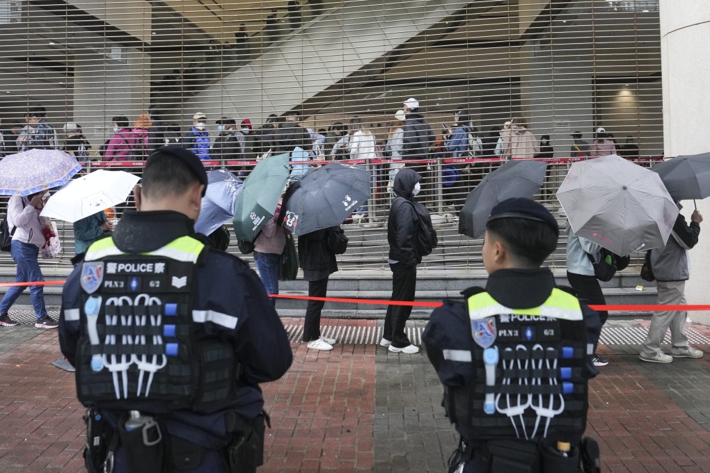 Police stand guard as people line up outside West Kowloon Court on Tuesday. Photo: Elson Li