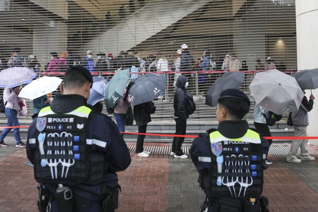 Police stand guard as people line up outside West Kowloon Court on Tuesday. Photo: Elson Li