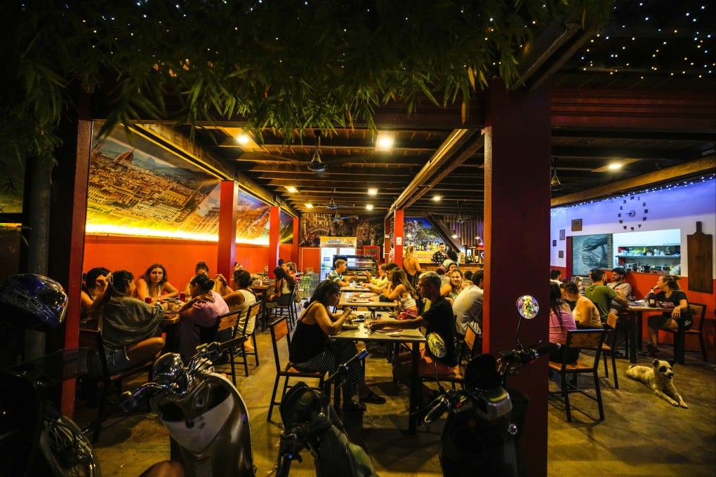 Foreign tourists have drinks and pizza at a restaurant in Vang Vieng, Laos, on Tuesday. Photo: Ap
