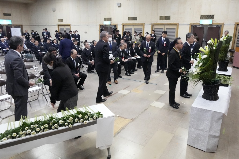 Guests offer a flower during a memorial ceremony for the Sado Island Gold Mine in Sado, Niigata prefecture, Japan as several seats reserved for South Korean delegates remained empty. Photo: AP