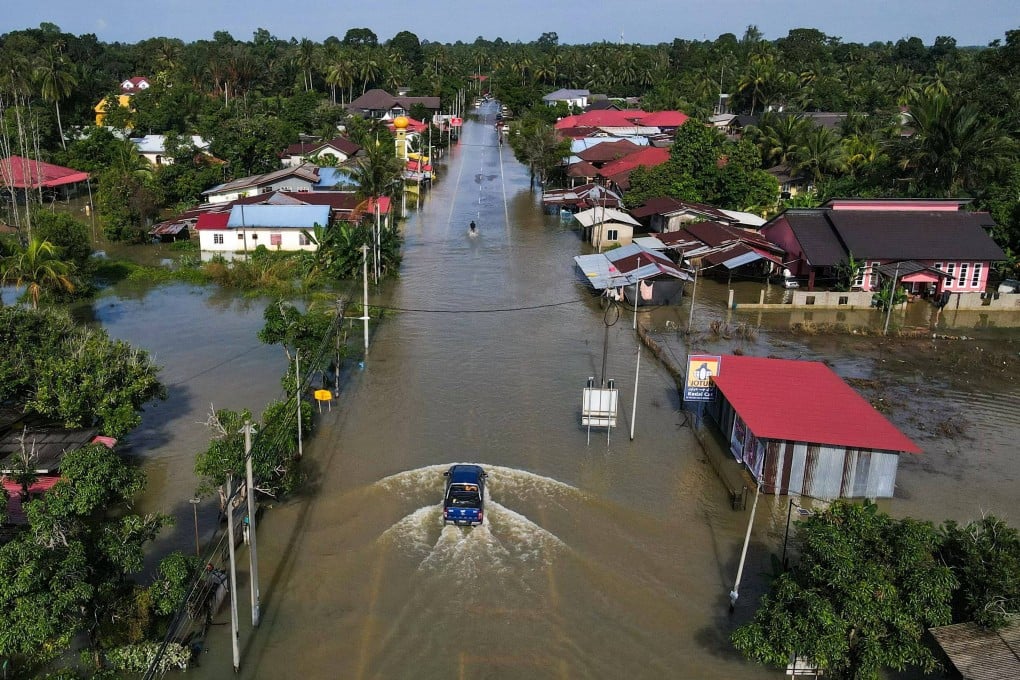 Vehicles traverse a flooded road in Malaysia’s Kelantan state on Monday after heavy rain. Photo: AFP