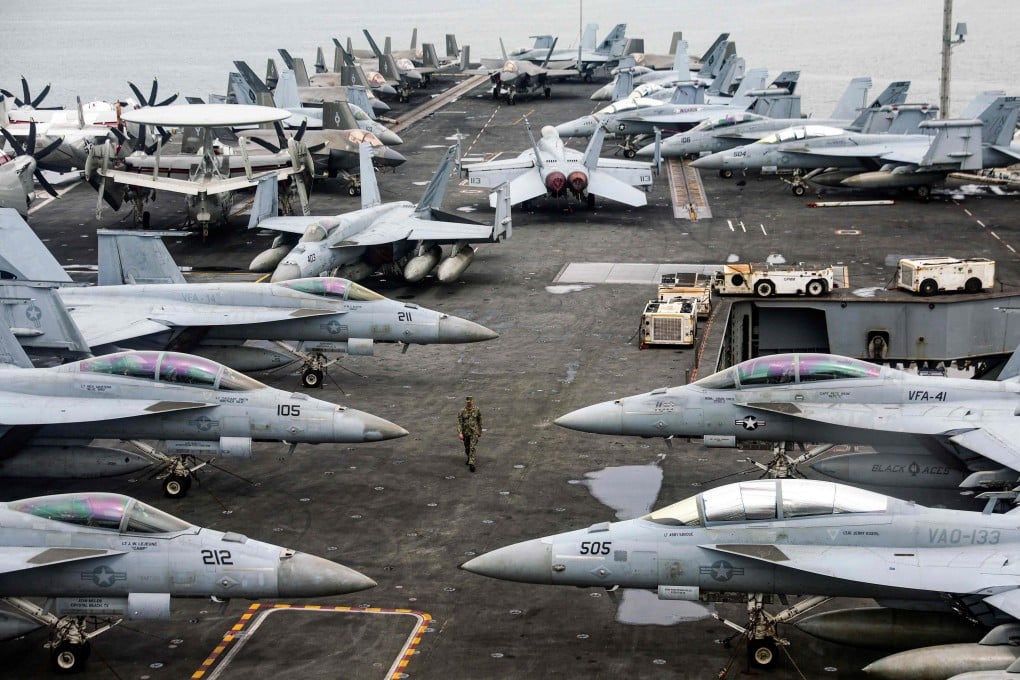 A US Navy officer walks past fighter jets parked on the flight deck of the Nimitz-class aircraft carrier USS Abraham off the coast of Malaysia on November 26. Photo: AFP