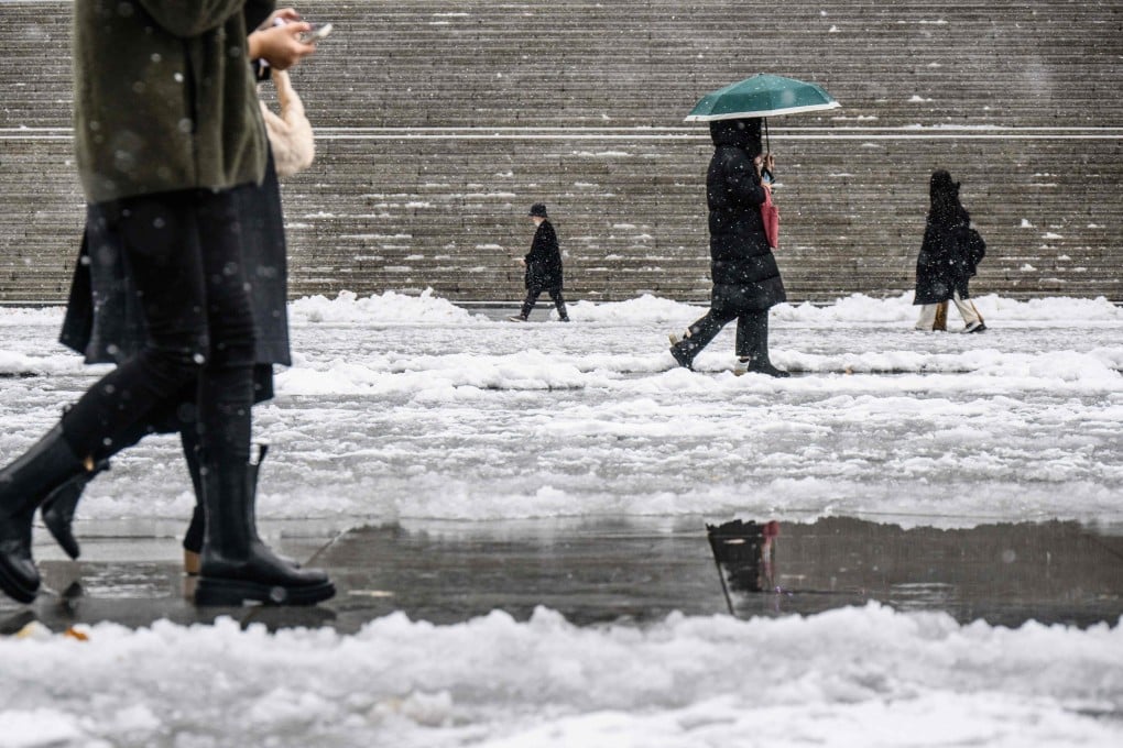 People walk amid heavy snowfall in central Seoul’s Gwanghwamun Square last month. Photo: AFP