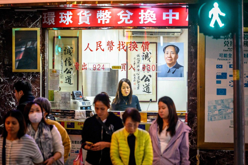 A portrait of the late Chinese leader Mao Zedong watches over a currency exchange bureau showing renminbi rates in Hong Kong on November 29. A weaker currency gives China immunity against US financial aggression. Photo: AFP