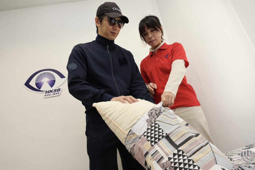 Cheng Kwok-kwong (left), who is slowly losing his vision due to a genetic disease,  gets instruction in changing bedding at the rehabilitation centre of The Hong Kong Society for the Blind. Photo: Jelly Tse