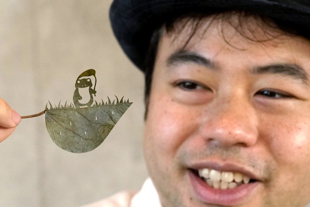 Lito holds up one of his freshly cut works in Tokyo. The Japanese leaf-cutting artist spends hours at a time carving his works, in a process that has helped him deal with ADHD. Photo: AP