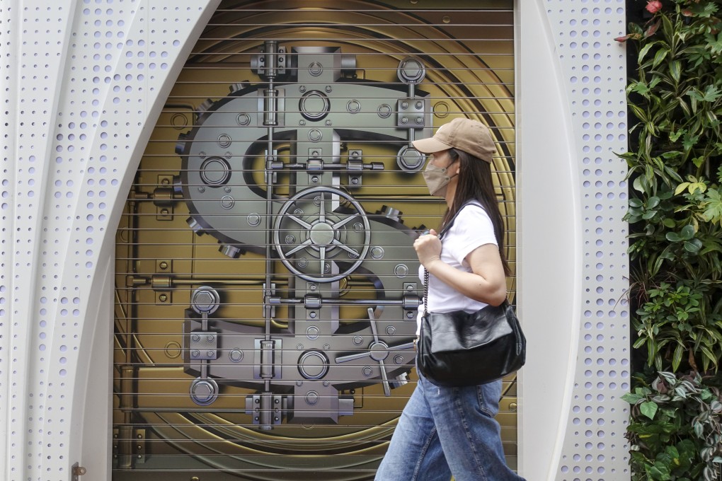 A woman walks past a currency-exchange shop in Causeway Bay with a bank vault painted on its gate, on May 5, 2024. Photo: Jelly Tse