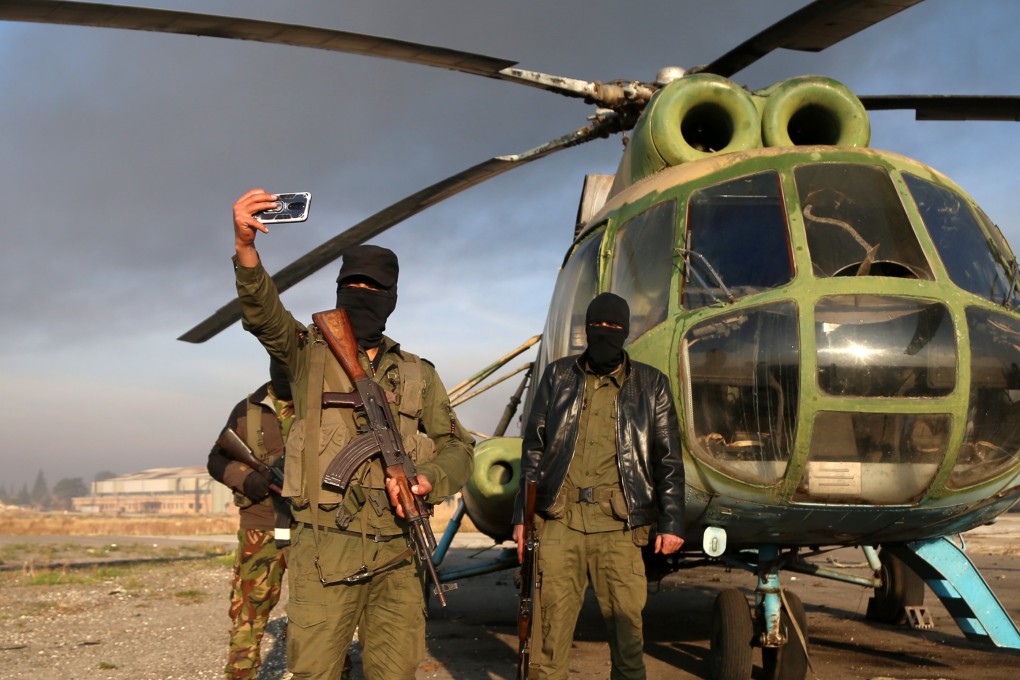 Armed men take selfies at the Nayrab military airport, in Aleppo, Syria. Photo: EPA-EFE