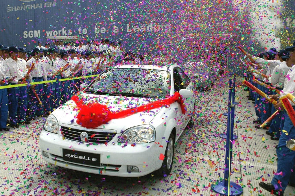 Chinese workers celebrate the first Buick Excelle sedan to roll off the production line at General Motor’s new facility in eastern Shanghai’s Pudong district, in May 2005. Photo: AP Photo