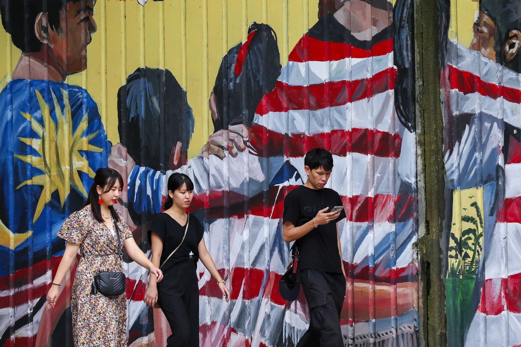 Tourists walk past a mural featuring the Malaysian national flag in Kuala Lumpur. Photo: EPA-EFE