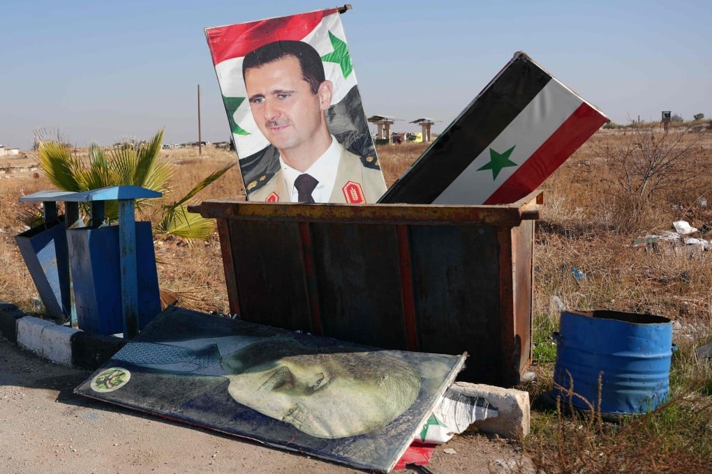 A portrait of Syria’s President Bashar al-Assad and a national flag are seen in a dumpster following the take-over of the Kweyris military airfield by rebel groups. Photo: AFP