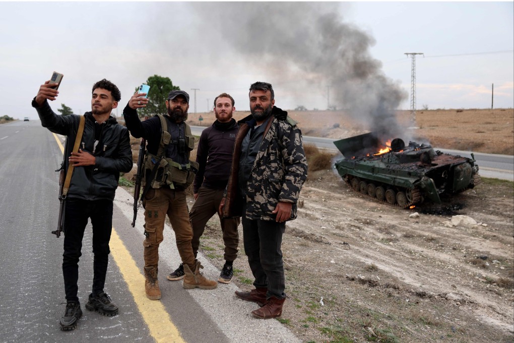 Armed men pose for pictures near a military vehicle belonging to the Syrian regime forces and seized by anti government forces, with rebels claiming they are on the verge of taking the capital Damascus. Photo: AFP