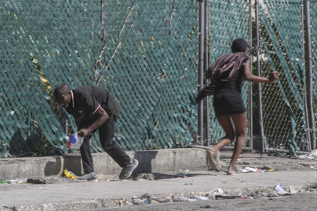 People take cover from gunfire during clashes between police and gangs in the Delmas neighborhood of Port-au-Prince, Haiti, on December 2. Photo: AP