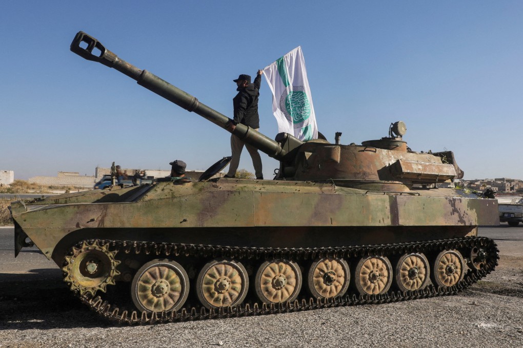 A rebel fighter stands atop of a military vehicle as he carries a Hayat Tahrir al-Sham flag in northwestern Idlib province, Syria on December 1. Photo: Reuters
