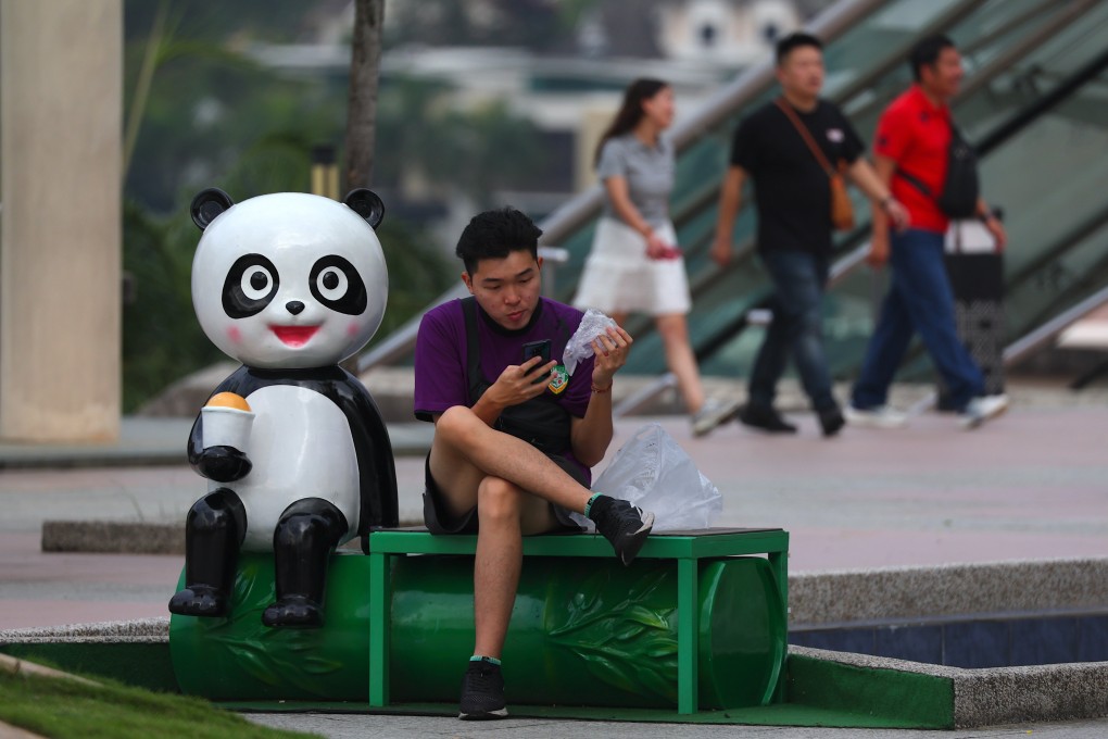 A man checks his phone near the Prime Minister’s Office in Putrajaya, Malaysia. Photo: EPA-EFE