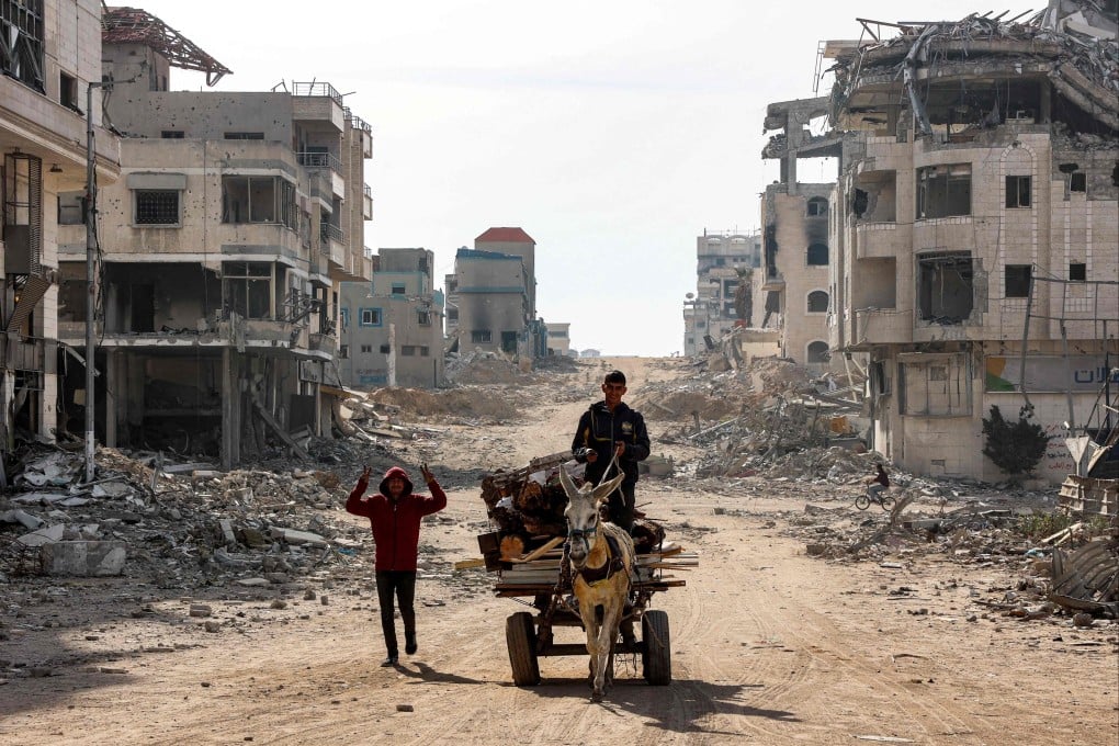 A youth walks next to a man driving a donkey-drawn cart loaded up with wood fragments to be used for firewood along a damaged street in Gaza City on Wednesday. Photo: AFP