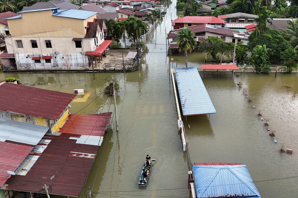 Residents ride a boat in a flooded area in Rantau Panjang, Malaysia’s Kelantan state, on December 3. Photo: Reuters