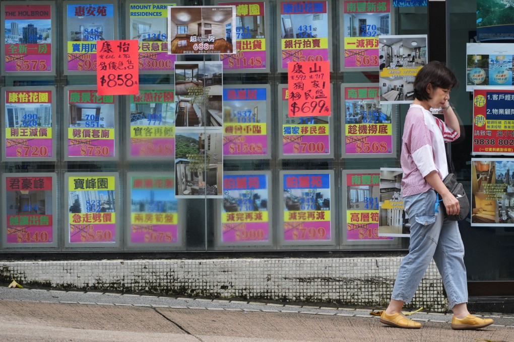 A woman walks past a real estate agency in Tai Koo featuring properties where prices have been slashed, on July 24. Photo: Eugene Lee