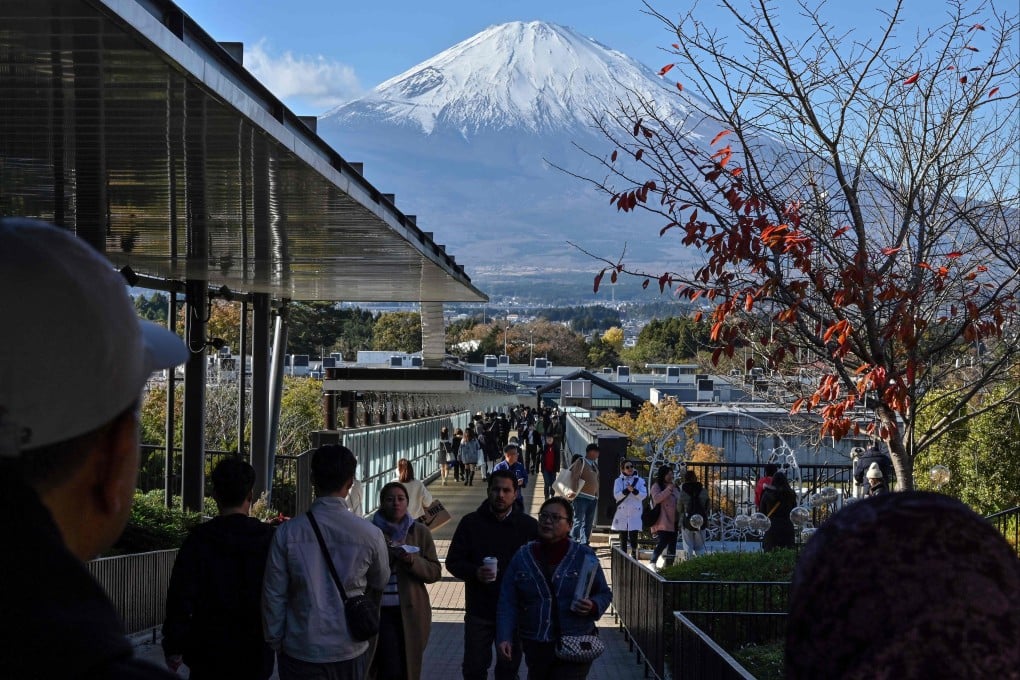 Mount Fuji is pictured in the background as people walk around a popular outlet shopping centre in the city of Gotemba, Shizuoka prefecture, on November 28. Photo: AFP