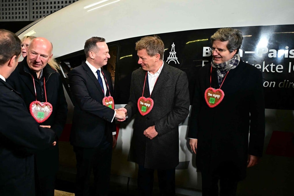 Wearing a traditional Christmas gingerbread reading Bon voyage (“‘good trip”), French ambassador to Germany Francois Delattre (right) reacts as the chief executive of German railway operator Deutsche Bahn Richard Lutz (second from right) shakes hands with German Minister for Transport Volker Wissing (centre) before the departure of the first daytime Berlin-Paris high-speed train. Photo: AFP