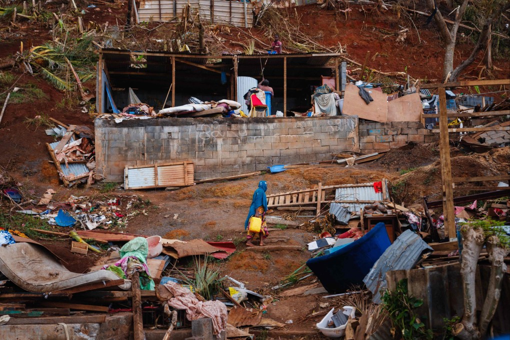 A woman climbs a hill through debris of destroyed shelters in the village of Bouyouni, on the French Indian Ocean territory of Mayotte. Photo: AFP