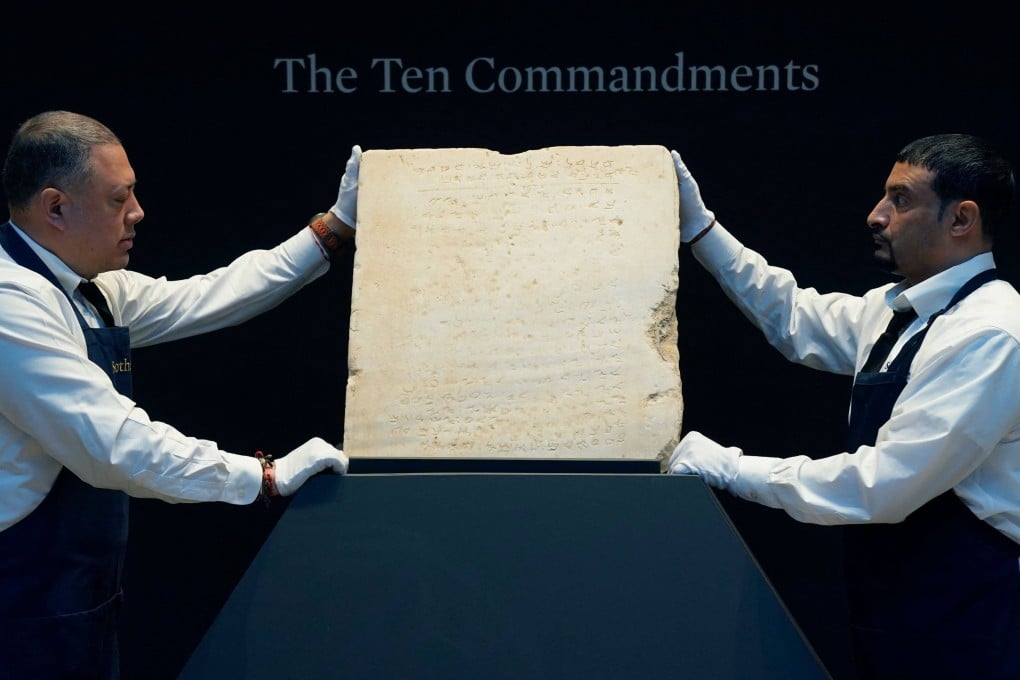 Sotheby’s workers hold what is said to be the oldest known inscribed stone tablet of the Ten Commandments during a press preview in New York on December 9. Photo: AFP