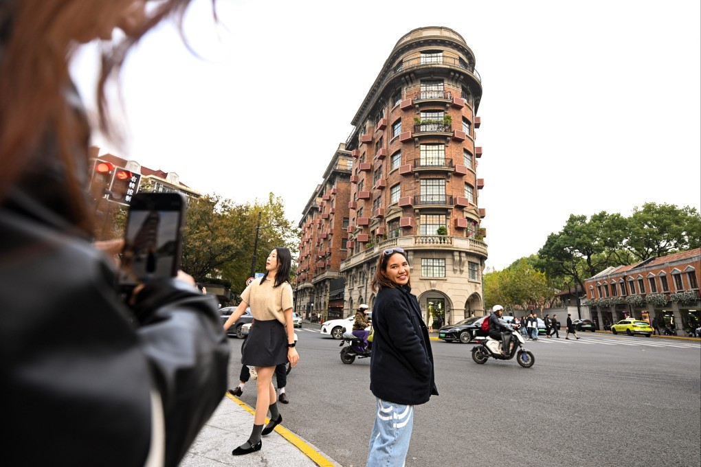 A tourist from Thailand poses for a photo in front of the Wukang Building in Shanghai on December 3. Photo: Xinhua