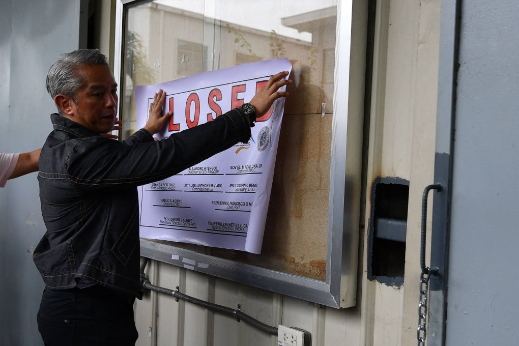 Philippine Interior Secretary Juanito Remulla places the closure sign on a Pogo hub in Cavite province on Tuesday. Photo: AFP