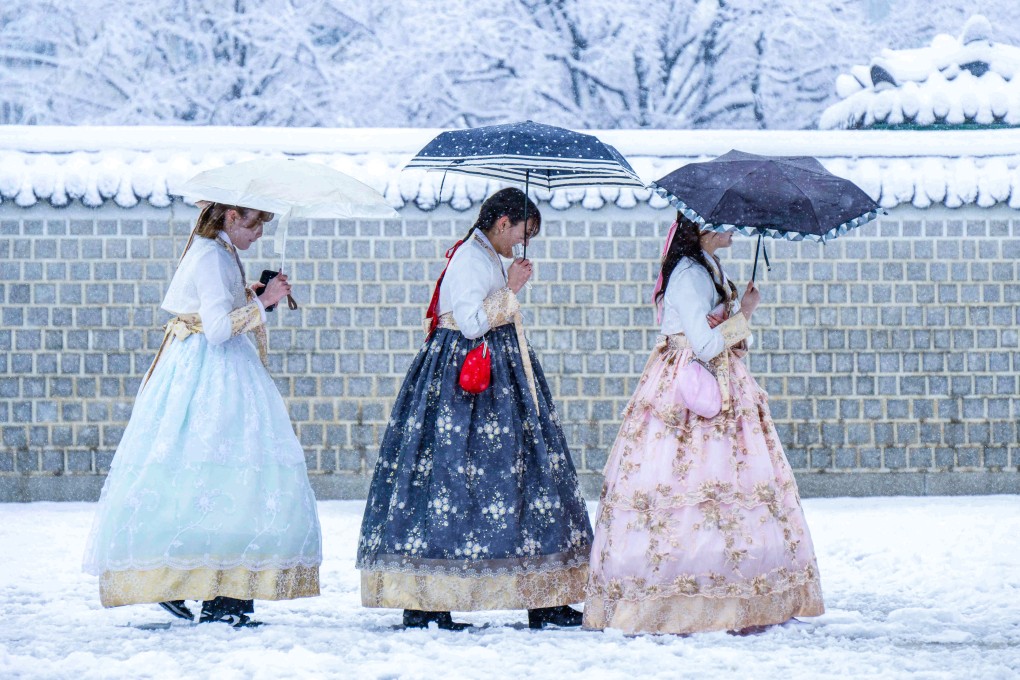 Visitors in traditional dresses on the grounds of Gyeongbokgung Palace amid heavy snowfall in Seoul in late November. Photo: AFP