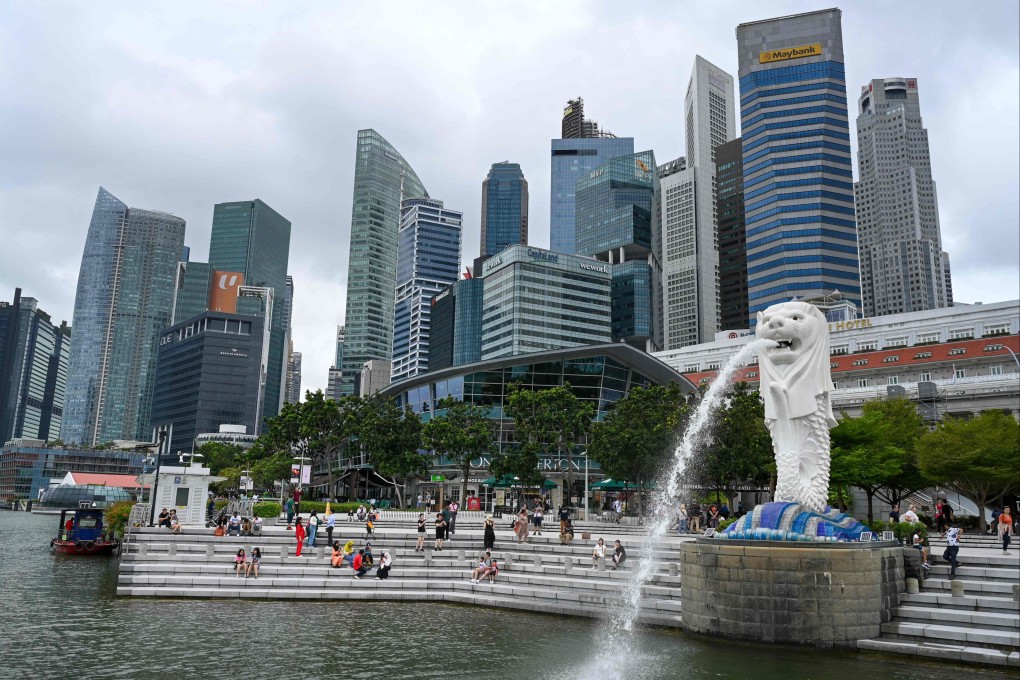 People sit near the Merlion statue in Singapore. Singapore’s law ministry has invoked the fake news law against Bloomberg and three other news sites. Photo: AFP