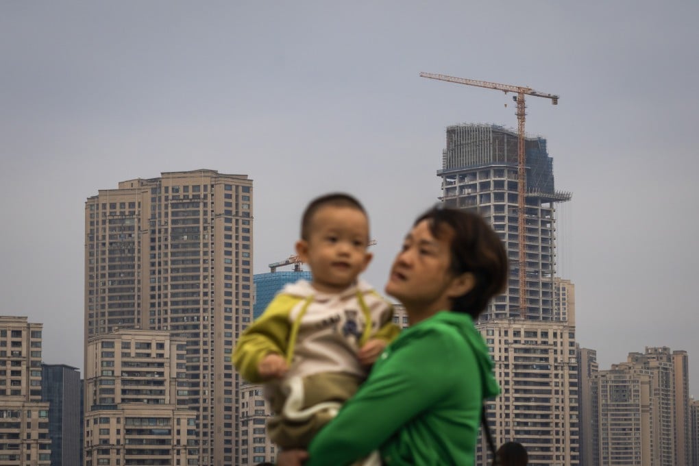 A mother held her child with high-rise buildings and a construction site in the background in Chongqing. Photo: Getty Images