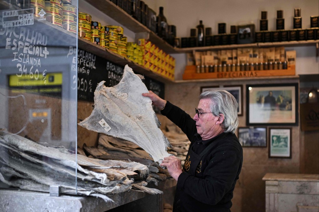 Jose Martins, 81, chooses a piece of salt cod for a customer at the Manteigaria Silva grocery shop in Figueira Square, Lisbon. It is traditionally served at Christmas in Portugal. Photo: AFP