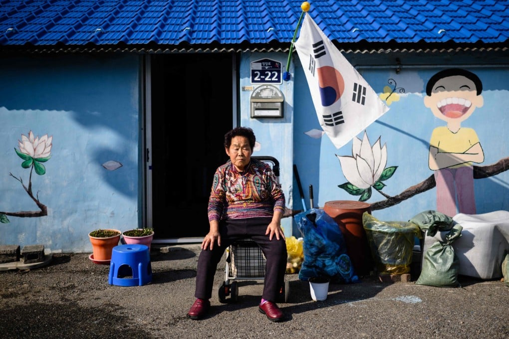 An elderly woman rests her eyes while sitting in front of a mural outside a property in Dongducheon, Gyeonggi Province. Photo: AP
