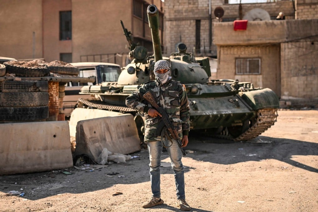 A rebel fighter poses in front of an abandoned tank in the town of Adra on the northeast outskirts of Damascus. Photo: AFP