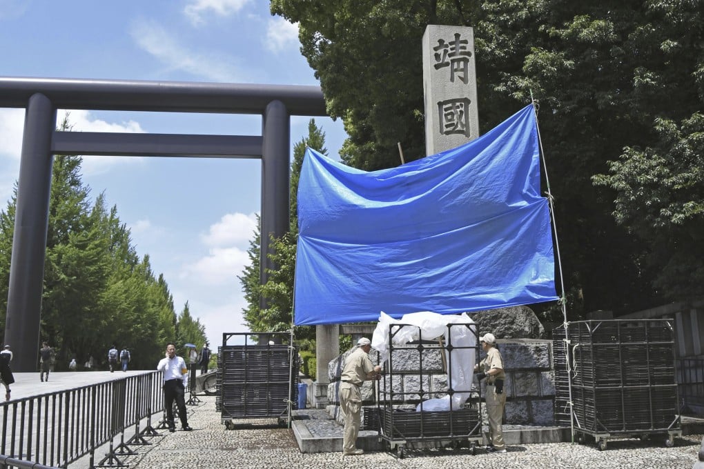 Workers prepare to remove graffiti on a pillar at Yasukuni Shrine in Tokyo in June. Photo: Kyodo via AP