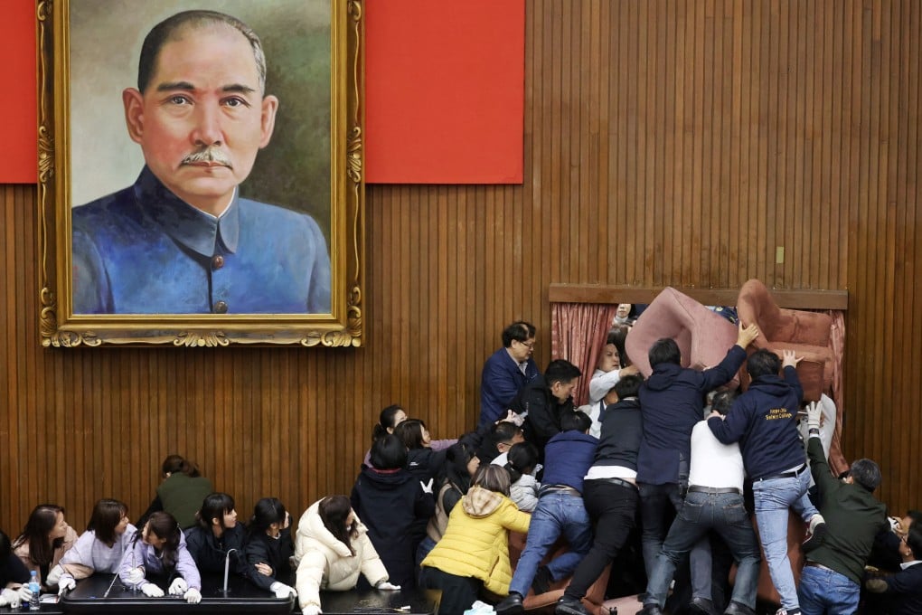 Opposition Kuomintang lawmakers (in white) trying to enter the Legislative Yuan, which the ruling Democratic Progressive Party (DPP) has barricaded with chairs, on December 20. Photo: AFP