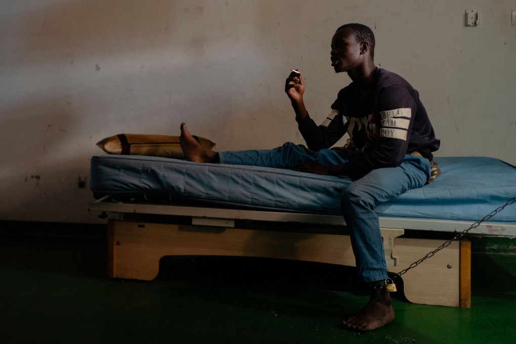 A young man smokes a cigarette while chained to his bed in his room at the Nouakchott Centre for Specialised Medicine in Mauritania. Photo: AFP