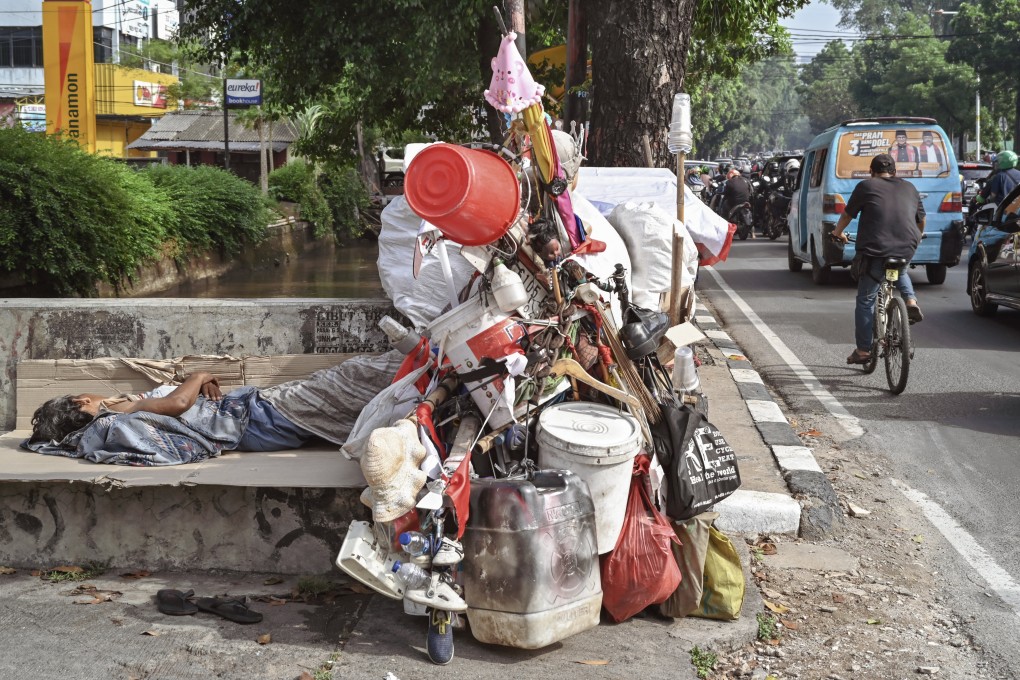 A homeless man sleeps on the street near his cart during the morning rush hour in Jakarta in November last year. Photo: AFP