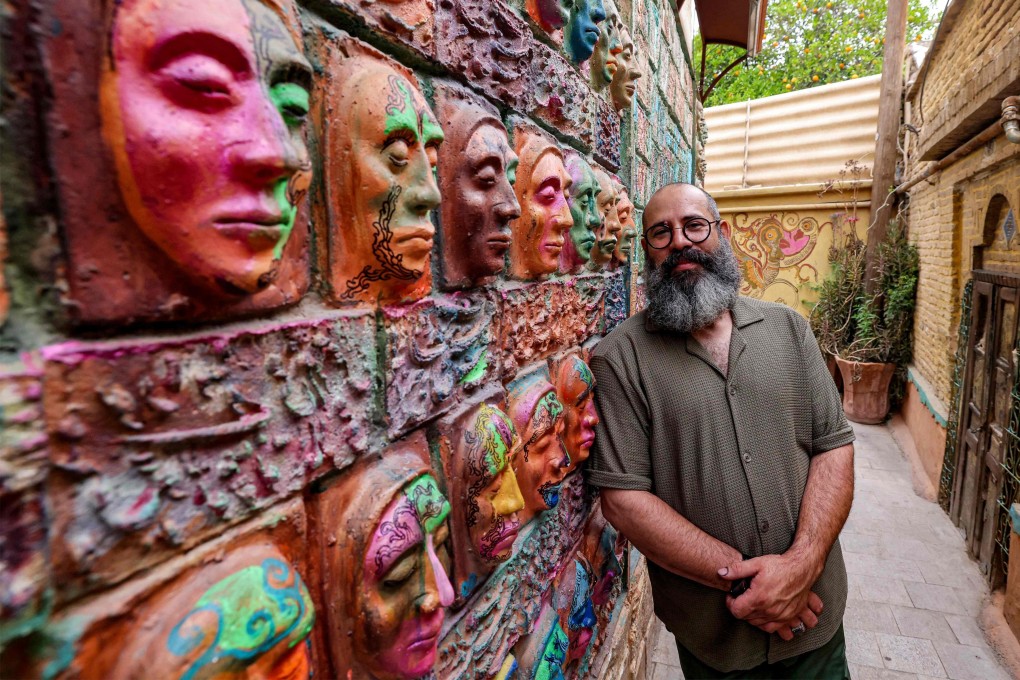 Iranian artist Adel Yazdi stands next to some of his high reliefs in an alley in Narenjestan, Shiraz, Iran on May 14, 2024. Photo: AFP