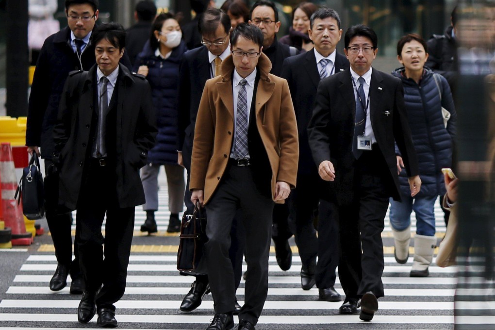 Commuters cross a road at a business district in Tokyo. Photo: Reuters