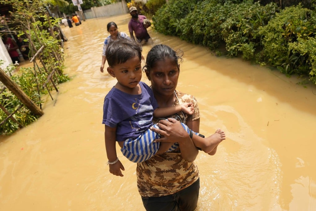 A Sri Lankan woman carries a child as she wades through a flooded street north of Colombo, Sri Lanka, in 2021. Photo: AP