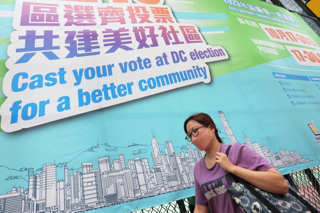 A woman walks past a promotional poster for the 2023 district council elections. Photo: Jelly Tse